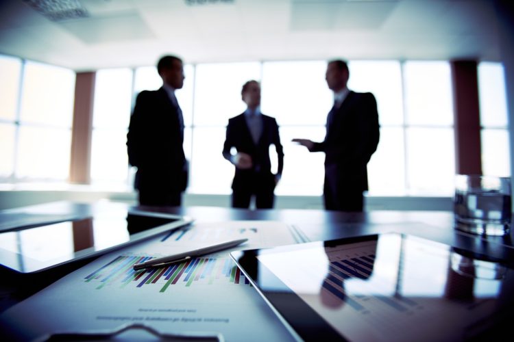 close-up-documents-with-businessmen-blurred-background